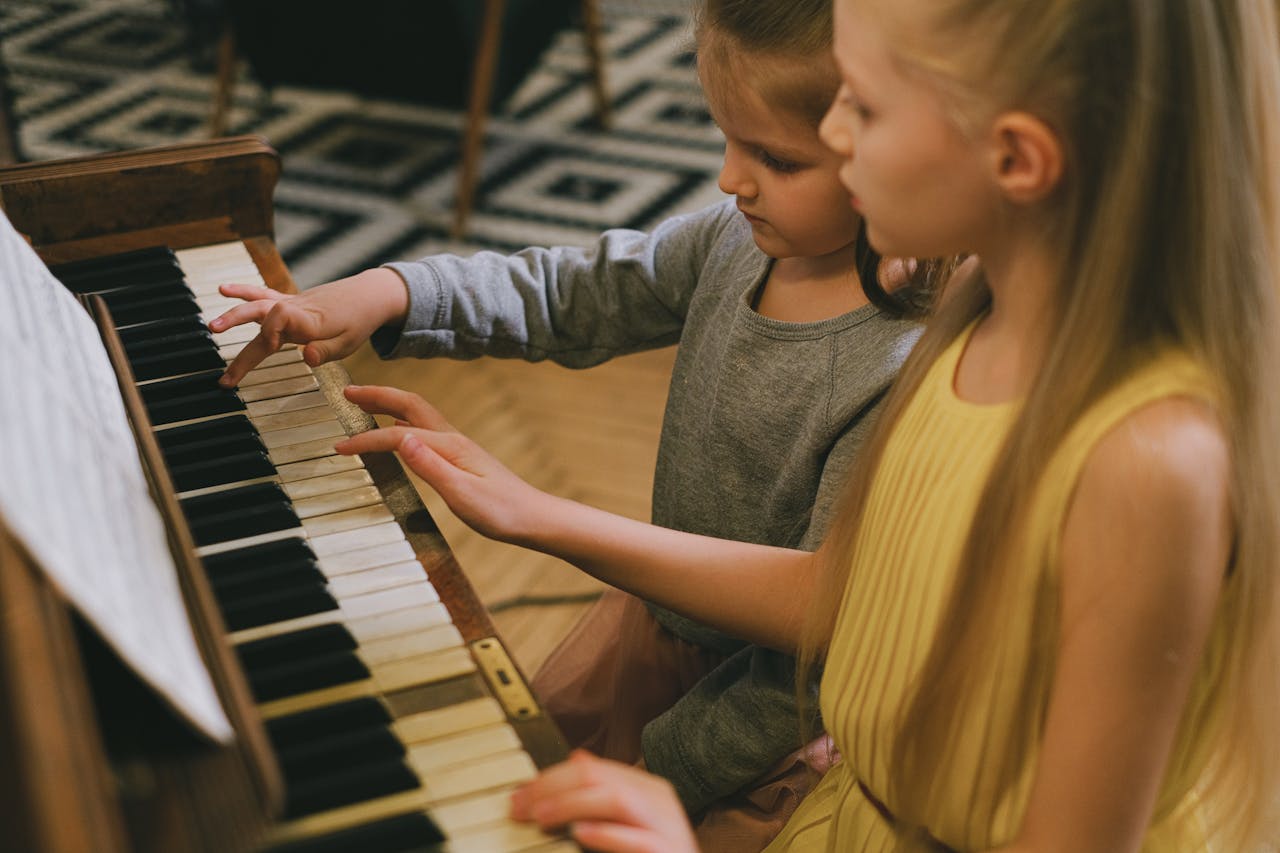 why-choose-us Two young girls playing piano together, sharing a musical moment indoors.