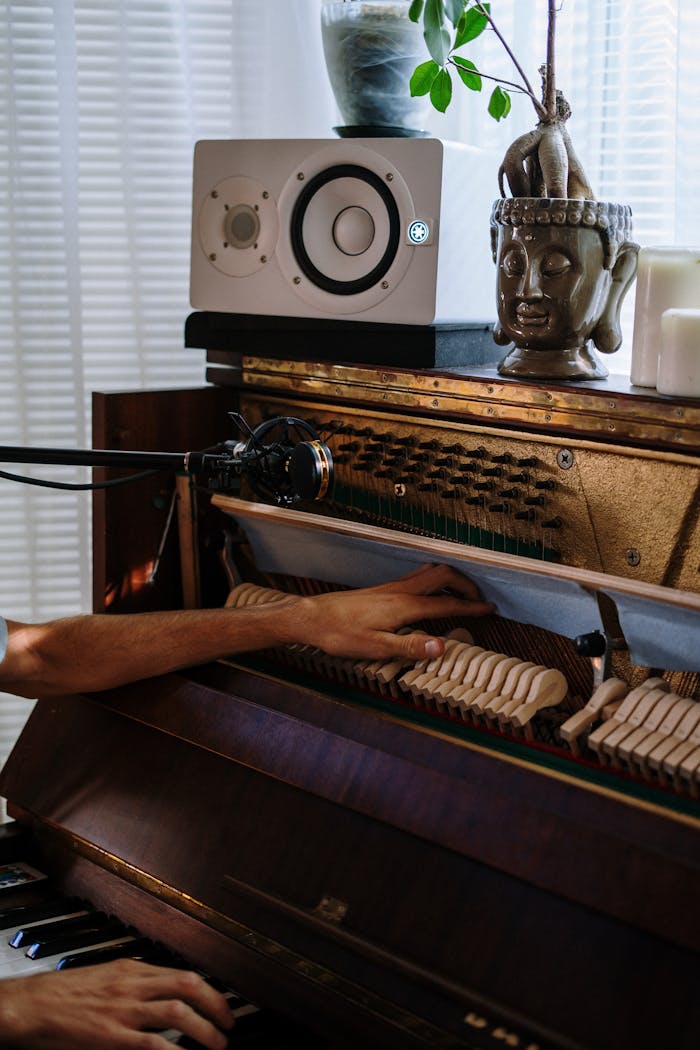 services-01 Hands tuning a grand piano with audio equipment in a home studio, creating a serene ambiance.